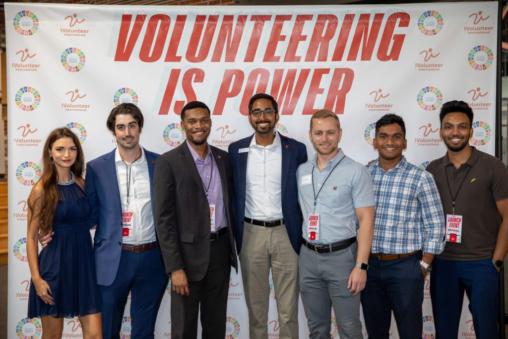 A group photo of people standing with the backdrop "volunteering is power" written.