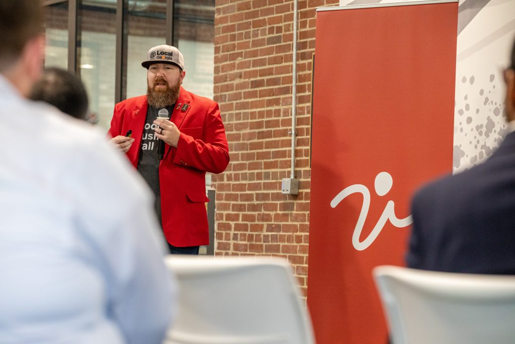 A photo of Nathan Stuck speaking at a session with the IVolunteer International banner behind him