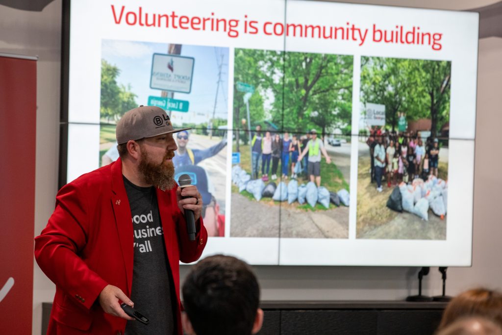 A photo of Nathan Stuck speaking with a slide deck behind him reading "volunteering is community building."