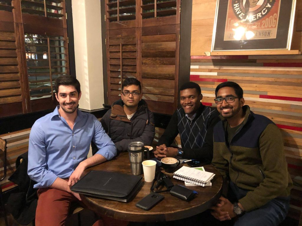 A picture of four team members seated around a table and posing for a photo.